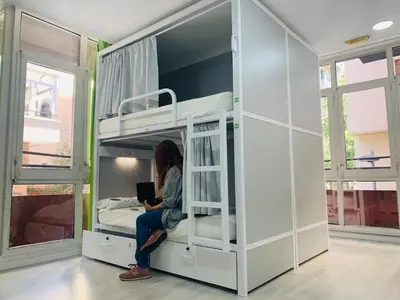 a woman sitting in a bunk bed with a laptop at Alberguinn in Barcelona