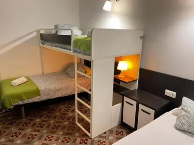 a small room with two bunk beds and a desk at Big Apartment Barcelona Gran via in Barcelona