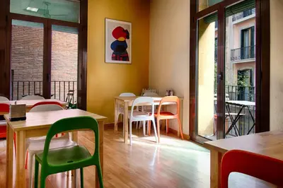 a dining room with tables and chairs and windows at Itaca Hostel in Barcelona