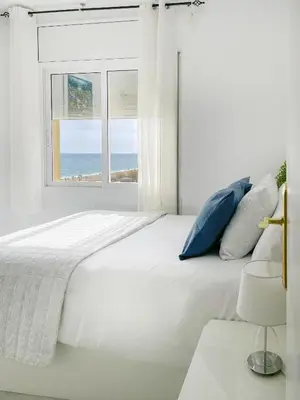 a white bedroom with a large bed and a window at fantasticas vistas a mar in Pineda de Mar