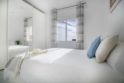 a white bedroom with a large white bed and a window at fantasticas vistas a mar in Pineda de Mar