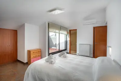 a bedroom with a large white bed and a window at Residential Tourist Apartments in Caldes d'Estrac