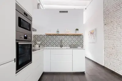 a kitchen with white cabinets and a stove top oven at Stylish Apartment with Terrace for Couple or Family in Barcelona