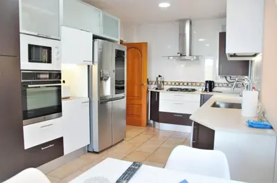 a kitchen with white cabinets and stainless steel appliances at VILLA SOFIA CALELLA in Calella