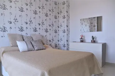 a bedroom with a bed and a wall with floral wallpaper at VILLA SOFIA CALELLA in Calella