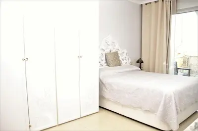 a white bedroom with a bed and a window at VILLA SOFIA CALELLA in Calella