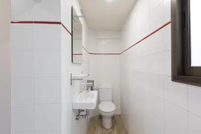 a white bathroom with a toilet and a sink at Hostal Oliveta in Barcelona