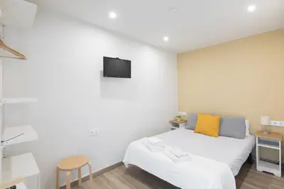 a bedroom with a bed and a tv on the wall at Hostal Oliveta in Barcelona