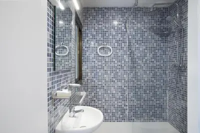 a bathroom with a sink and a shower with blue tiles at Hostal Oliveta in Barcelona