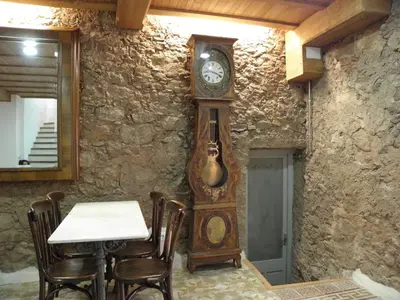 a grandfather clock in a room with a table at Hostal Cal Pla in Sant Llorenc Savall