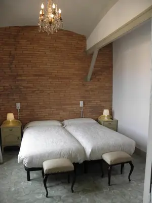 two beds in a bedroom with a brick wall at Hostal Cal Pla in Sant Llorenc Savall