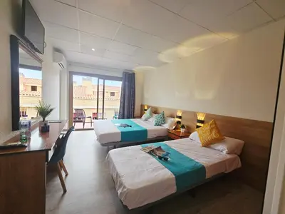 a hotel room with two beds and a desk at Hotel Mar i Sol in Calella