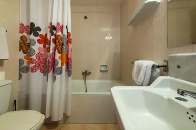 a bathroom with a sink and a toilet and a shower curtain at Hotel Mar i Sol in Calella