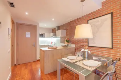 a kitchen with a table and a brick wall at Serennia Cest Apartamentos Arc de Triomf in Barcelona
