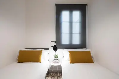 two beds in a white room with yellow pillows at Aspasios Sagrada Familia Apartments in Barcelona