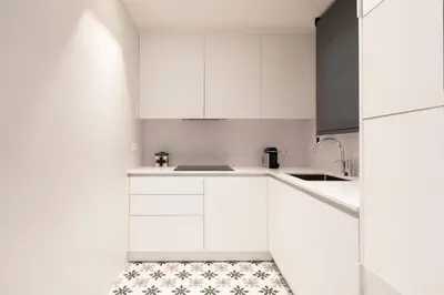 a white kitchen with white cabinets and a tile floor at Aspasios Sagrada Familia Apartments in Barcelona