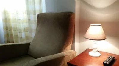a lamp sitting on a table next to a chair with a remote control at Hostal LK Barcelona in Barcelona