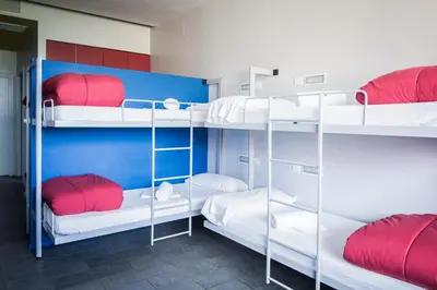 a room with four bunk beds with red and white pillows at Centre Esplai Albergue in El Prat de Llobregat