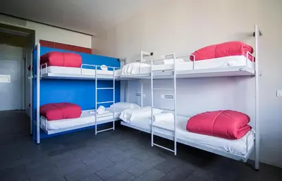 a room with three bunk beds with red and white pillows at Centre Esplai Albergue in El Prat de Llobregat