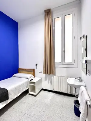 a bedroom with a bed and a sink and a window at Pensión Peiró in Barcelona