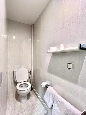 a white bathroom with a toilet and towels at Pensión Peiró in Barcelona