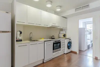 a kitchen with white cabinets and a washer and dryer at AB Montjuic in Barcelona