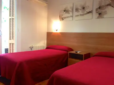 two beds in a room with red sheets on them at Hostal Madrazo in Barcelona