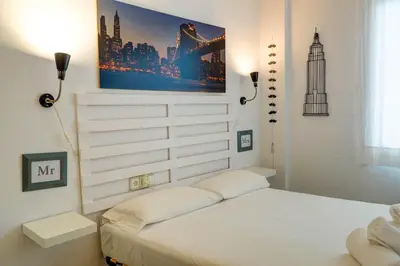 a bedroom with a white bed with a picture on the wall at Lucy Apartment by Hello Homes Sitges in Sitges