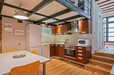 a kitchen with a table and a refrigerator and cabinets at Alcam Loft Grassot in Barcelona