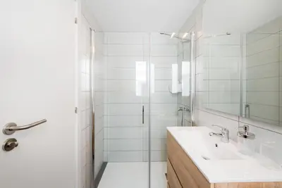 a white bathroom with a sink and a shower at Petit Luxe Dúplex in Terrassa