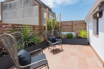 a patio with chairs and plants and a fence at Petit Luxe Dúplex in Terrassa