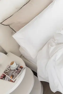 a bed with white sheets and a magazine on a table at El Palauet Modernist Suites Barcelona in Barcelona