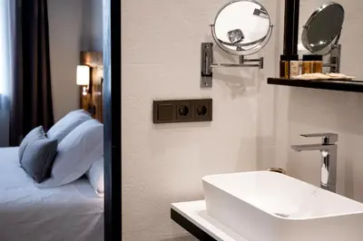a bathroom with a sink and a mirror and a bed at Sa Voga Hotel & Spa in Arenys de Mar
