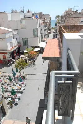 a city street with umbrellas and people sitting on chairs at Apartamento Montroig 3 Ático in Sitges