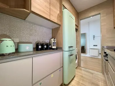 a kitchen with a white refrigerator and wooden cabinets at The Gaudi Suites in Barcelona