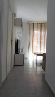 a hallway with a tv and a table and a window at Apartamentos Atlas Terrassa III in Terrassa