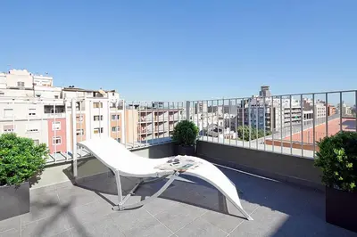 a white chair on a balcony with a view of a city at Charmsuites Paralel in Barcelona