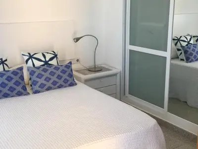 a bedroom with a bed with blue and white pillows at Solimar in Castelldefels