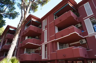 a red building with trees in front of it at Calm, Beach and Bikes in Castelldefels