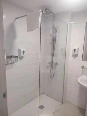a shower with a glass door next to a sink at Hotel Blauet by Bossh! Hotels in El Prat de Llobregat
