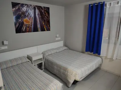 a bedroom with two beds and a window with blue curtains at Hotel Blauet by Bossh! Hotels in El Prat de Llobregat