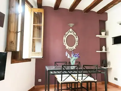 a dining room with a table and chairs against a burgundy wall at Top Barcelona Apartments in Barcelona