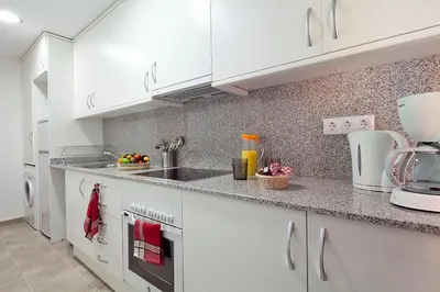 a kitchen with white cabinets and a counter top at Charmsuites Nou Rambla in Barcelona