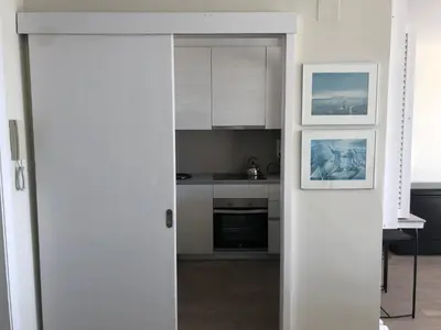 an open door to a kitchen with white cabinets at Ponent - Espectaculares vistas al mar in San Pol de Mar