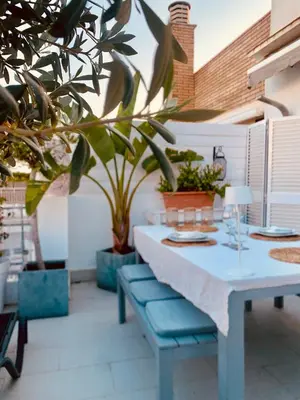 a table and bench on a patio with plants at Penthouse Sitges in Sitges