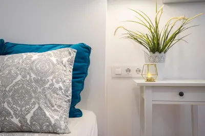 a blue pillow on a bed with a plant on a table at Hotelito Boutique Cinca in Hospitalet de Llobregat