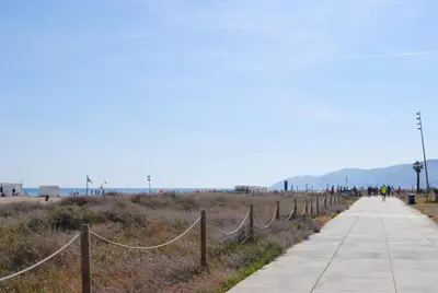 a sidewalk next to a beach with a fence at Apartamento Maraka Playa Castelldefels in Castelldefels