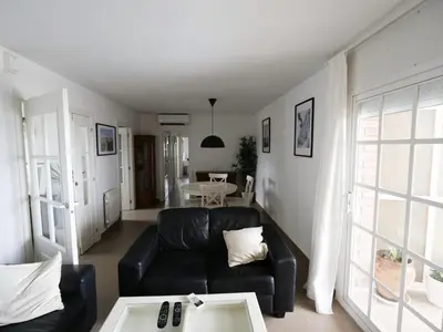 a living room with a black couch and a table at Apartamento Maraka Playa Castelldefels in Castelldefels