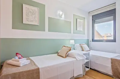 two beds in a room with a window at Alcam Badalona Playa Norte in Badalona