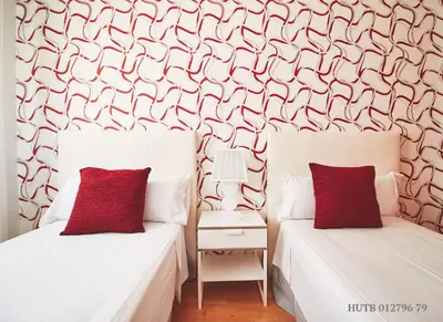 two beds with red pillows in a bedroom with a wallpaper at Alcam Badalona Playa Norte in Badalona